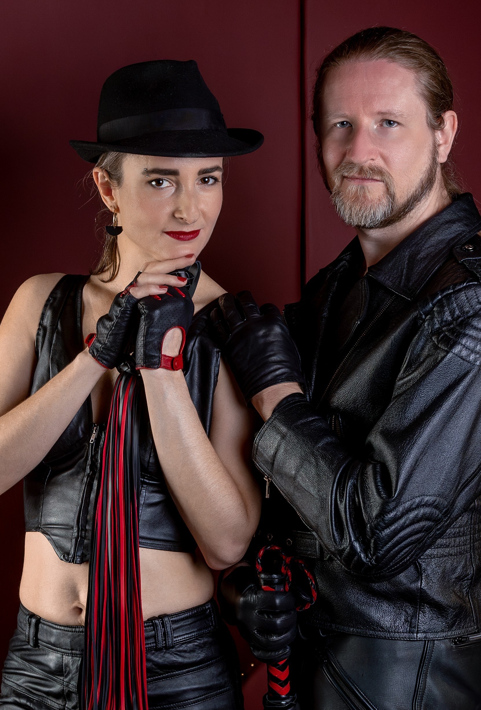 Hekate 10 mit Samael Foto von Hekate, einer großen, schlanken Domina mit Fedora und Flogger, zusammen mit Master Samael in Leder.