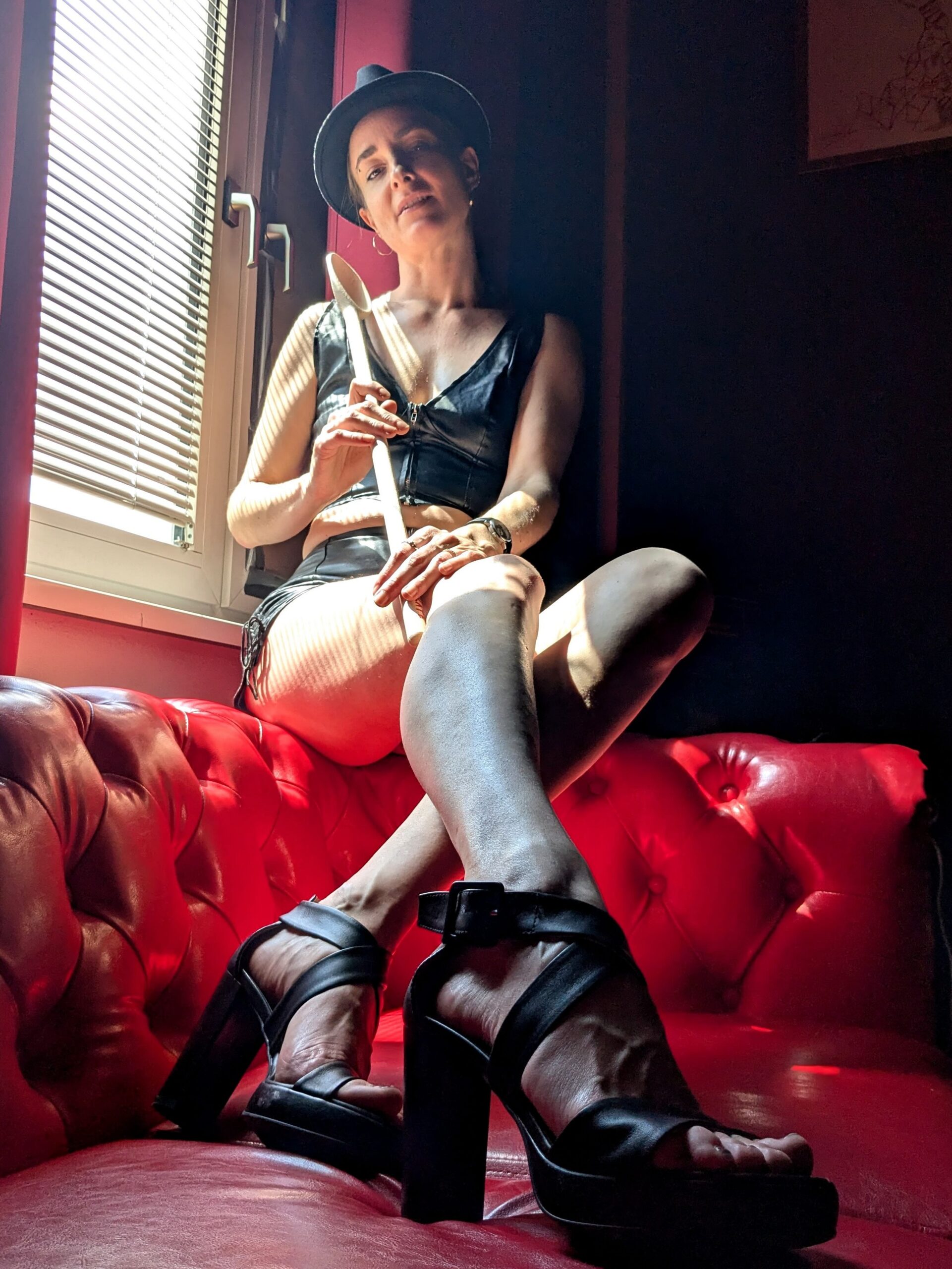 Hekate 7 Foto von Hekate, einer großen, schlanken Domina mit Fedora, Schlaginstrument und Absatzschuhen.