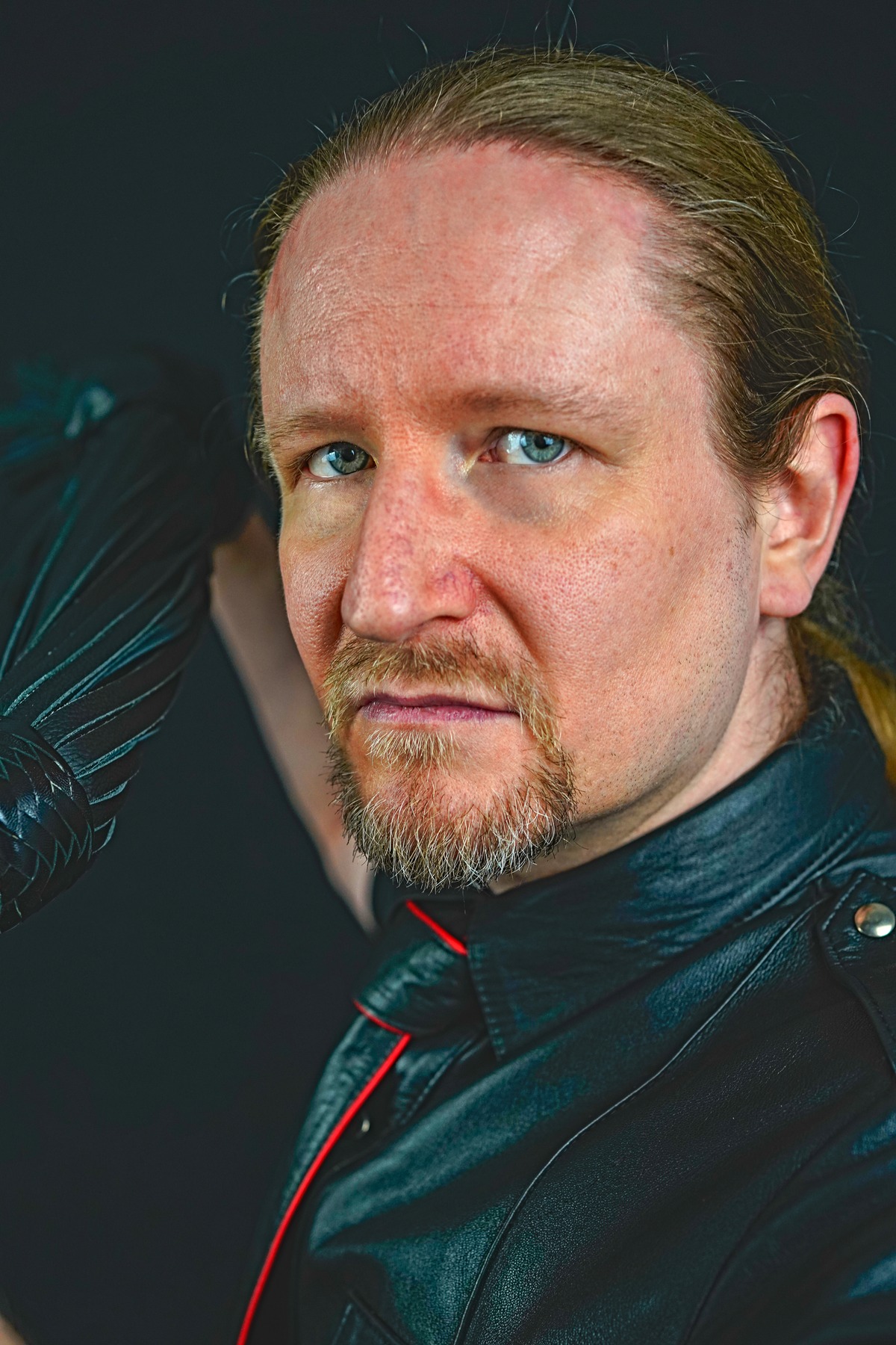 00_Master-Samael_Titelbild Portrait von Master Samael, einem blonden Profi-Dom mit blauen Augen in einem schwarzen Leder-Outfit.