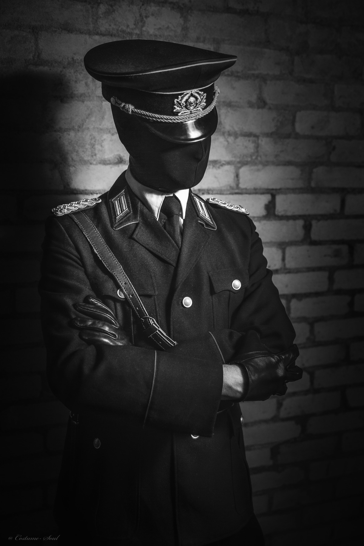 03_Master-Samael_Bild-3 Schwarz-weißes Foto von einem großen Mann in militärischer Uniform mit schwarzer Maske und einem schwarzen Hut. Das ist Master Samael.